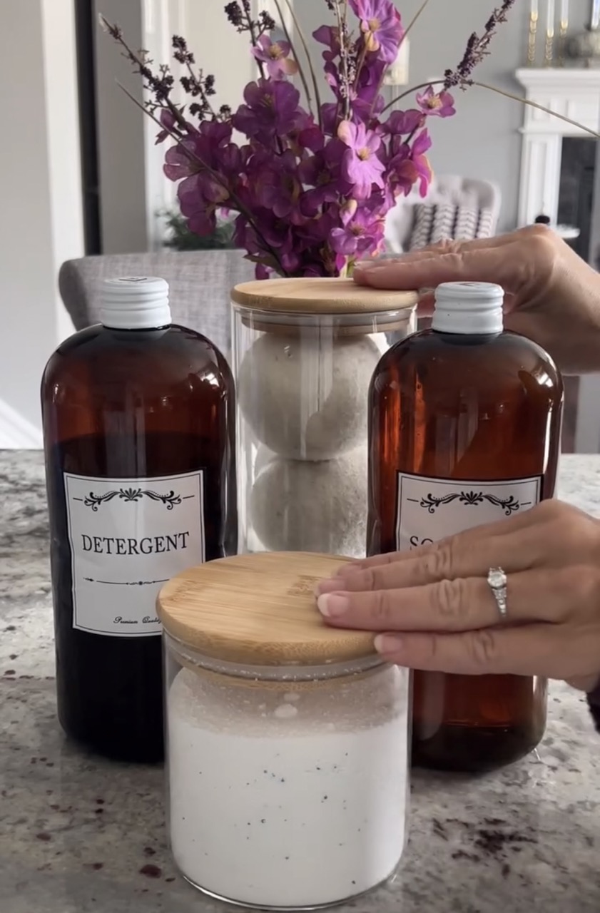 reveal image of 2 brown diy detergent bottles and 2 bamboo and glass jars with dryer balls and stain removal powder