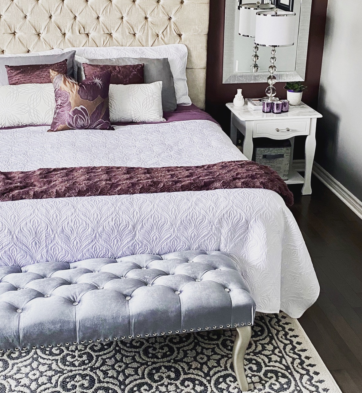 image of moody romantic bedroom makeover showing white bed, plum wall , white bedside table and silver velvet bench