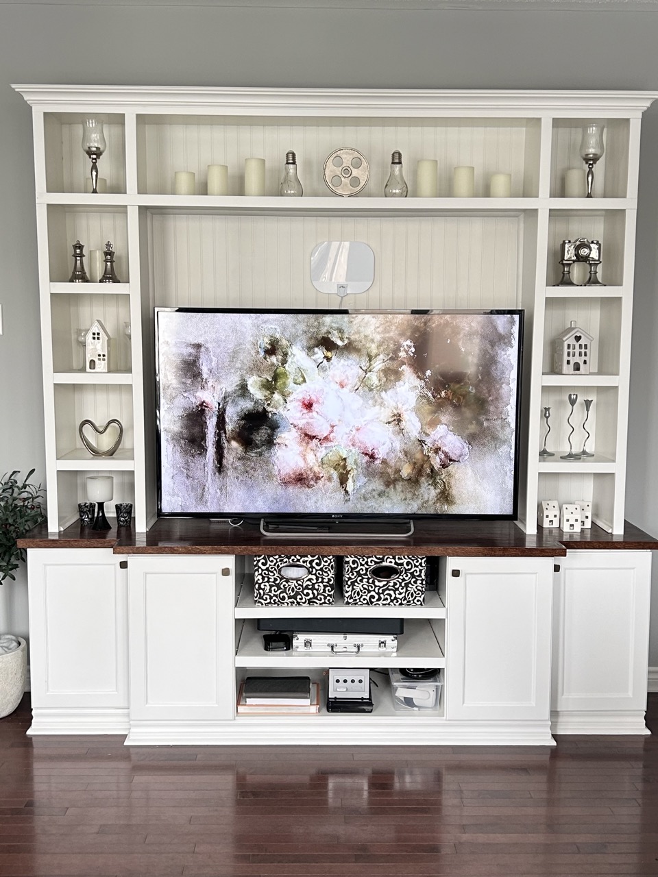 reveal image 2 the DIY wall unit build showing white wall unit with decor in side shelves and cupboard doors on the bottom