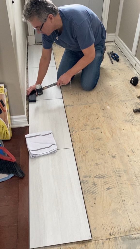 image of man installing new DIY front entryway white floor 