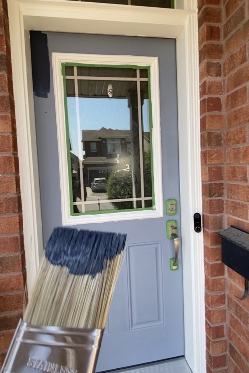image of front door primed with paint brush showing navy paint
